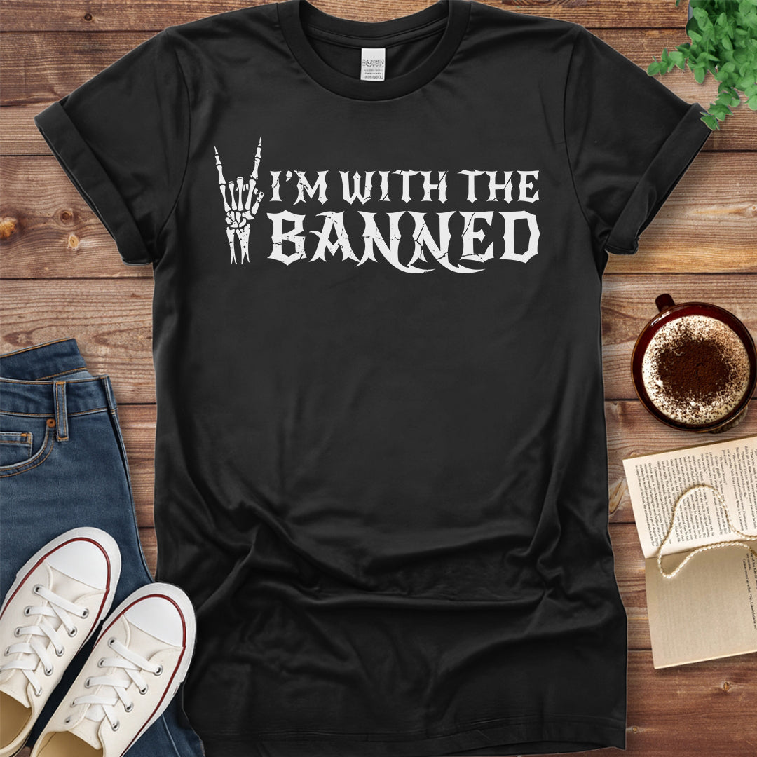 Black t-shirt with 'I'm with the banned' text on a wooden surface with jeans and sneakers.