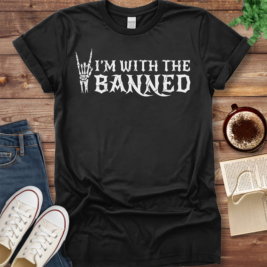 Black t-shirt with 'I'm with the banned' text on a wooden surface with jeans and sneakers.